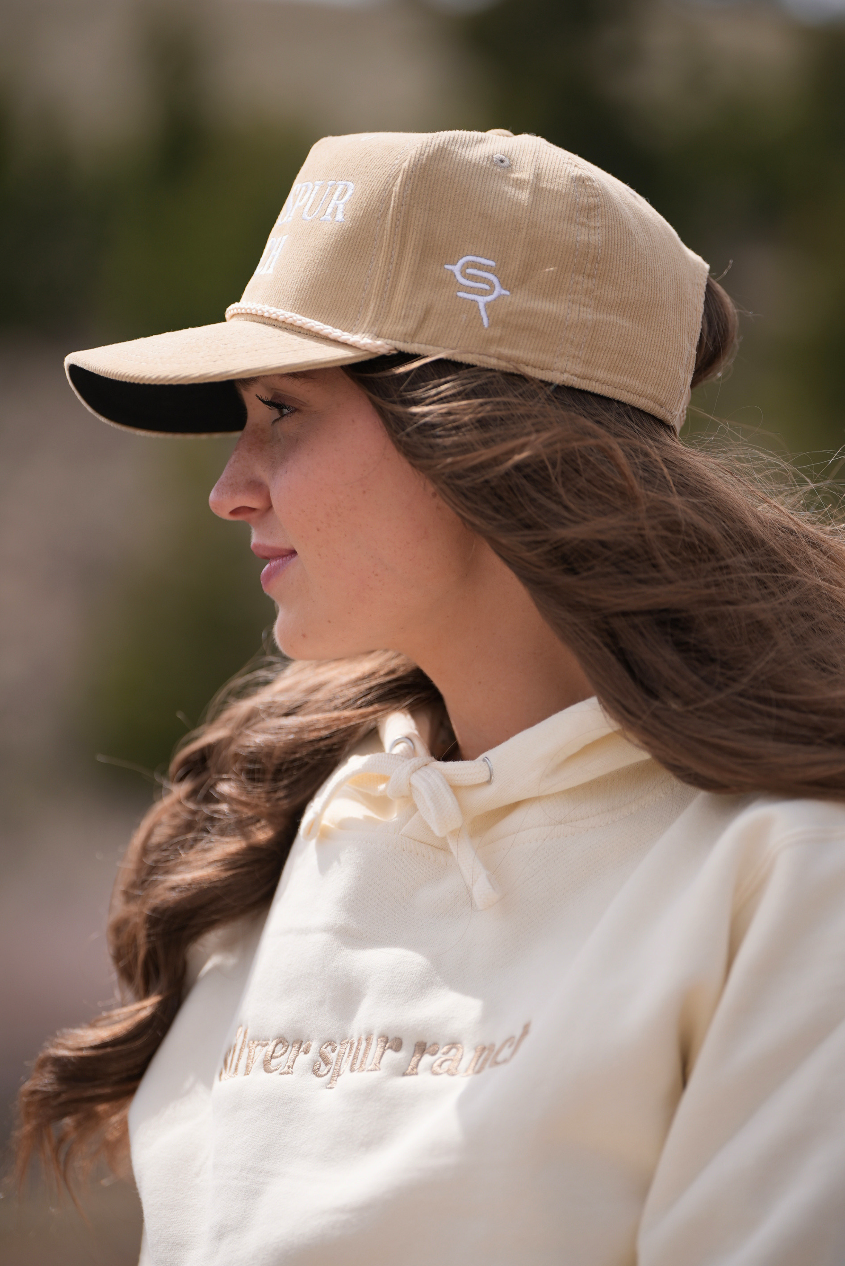 Woman wearing a beige corduroy rope hat featuring the 'Silver Spur Ranch' brand on the side.