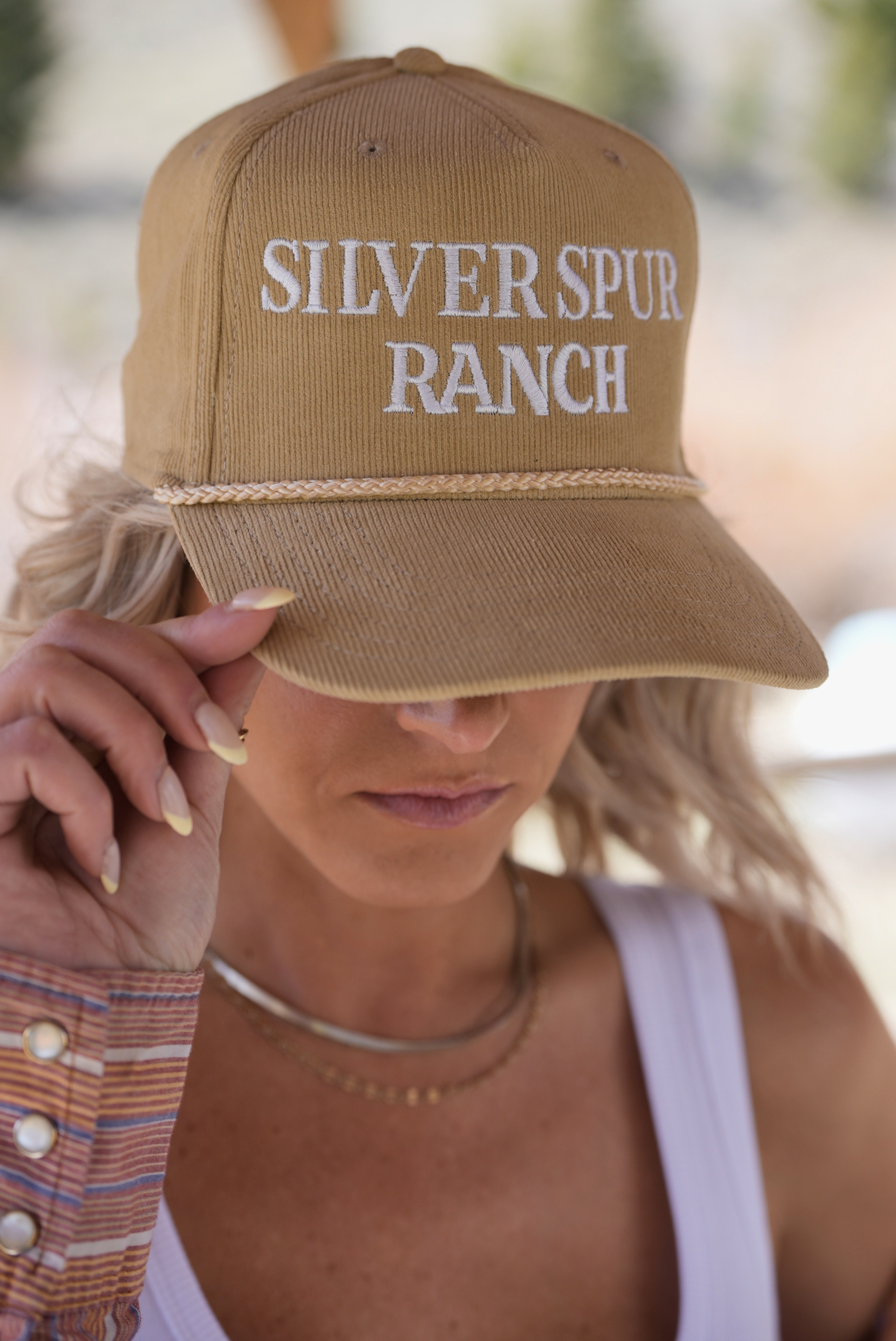 Woman wearing a beige corduroy rope hat featuring 'Silver Spur Ranch' on the front.