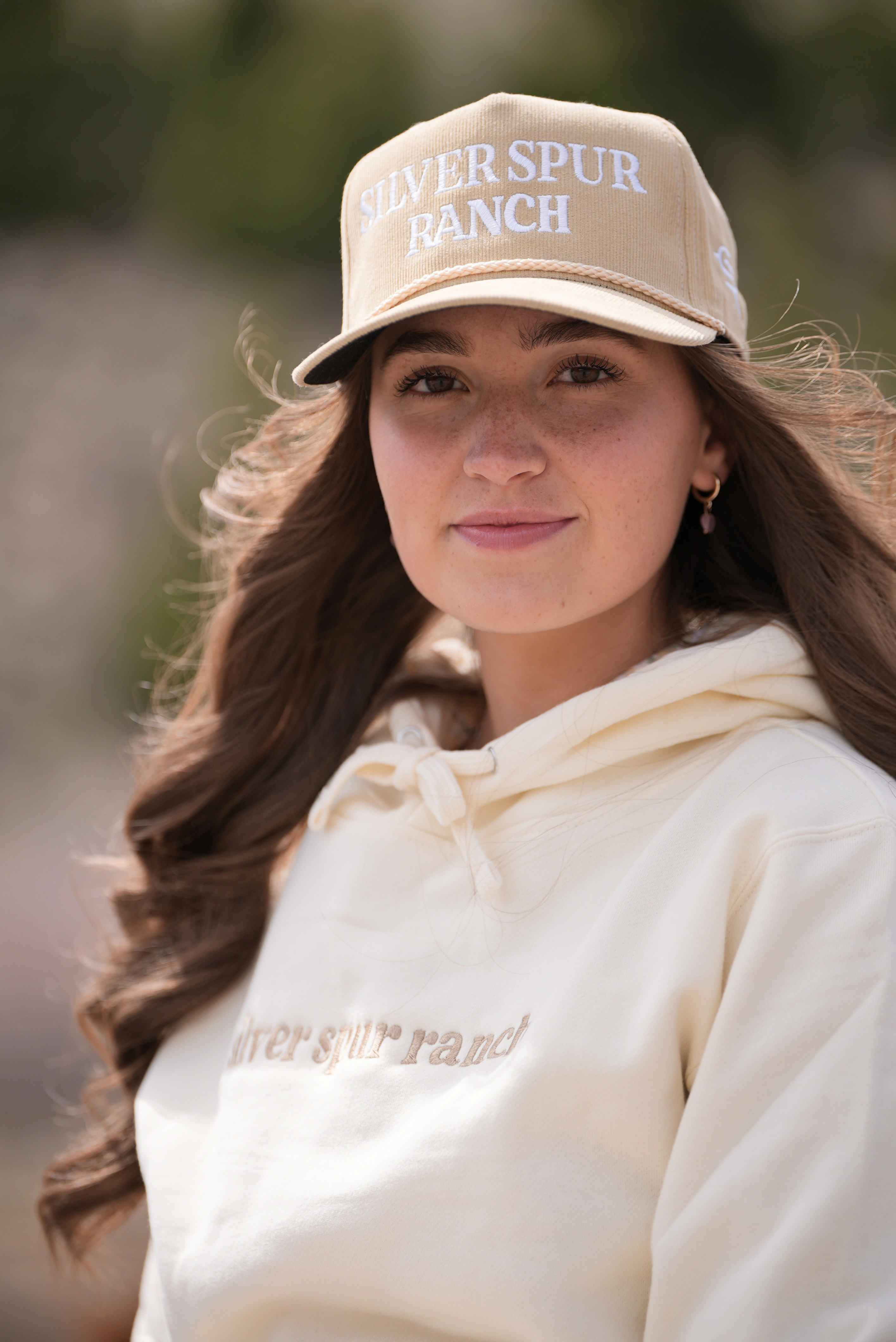 Woman wearing a beige corduroy rope hat featuring 'Silver Spur Ranch' across the front.