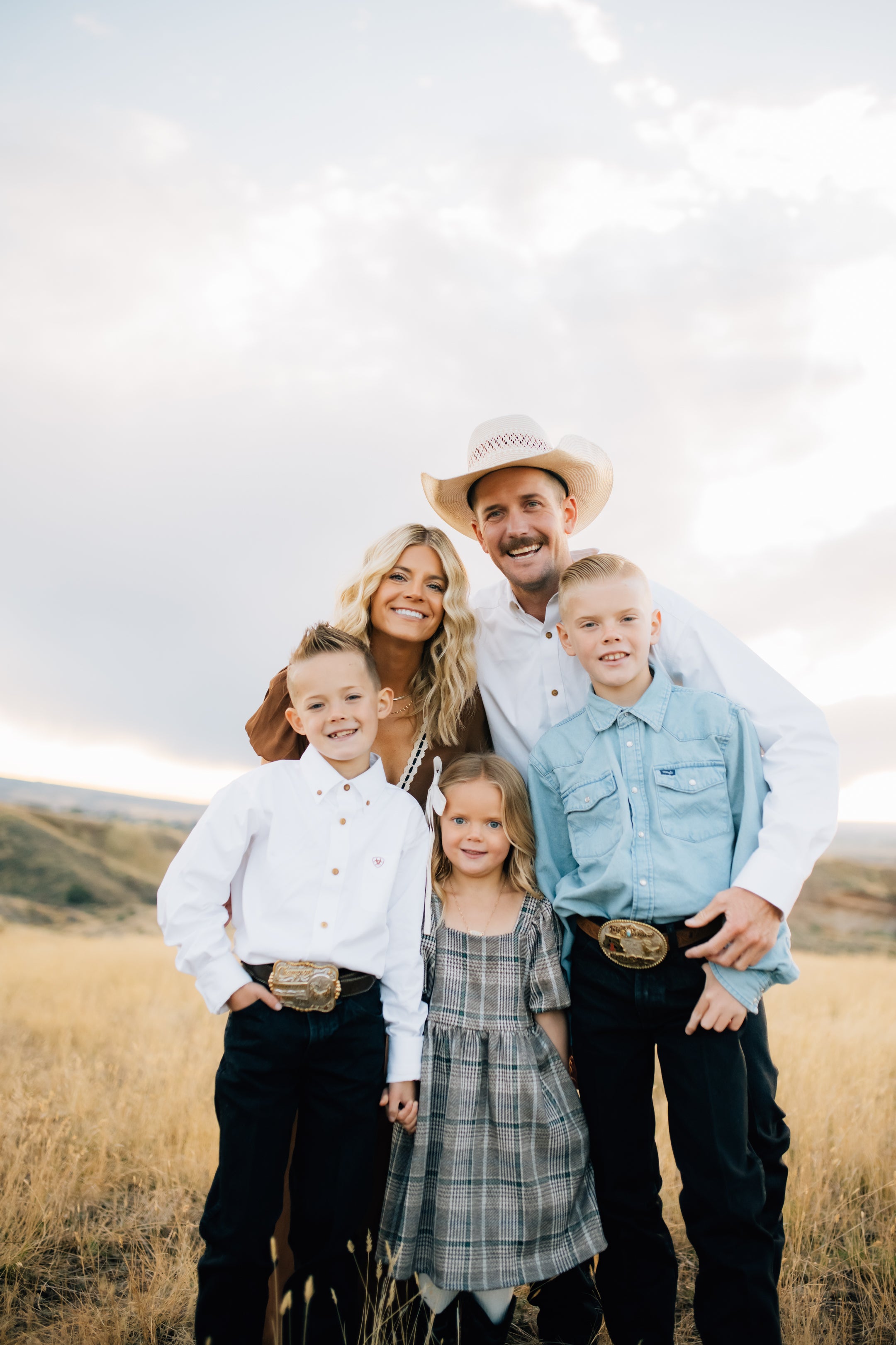 Family of four standing in a field with a scenic background