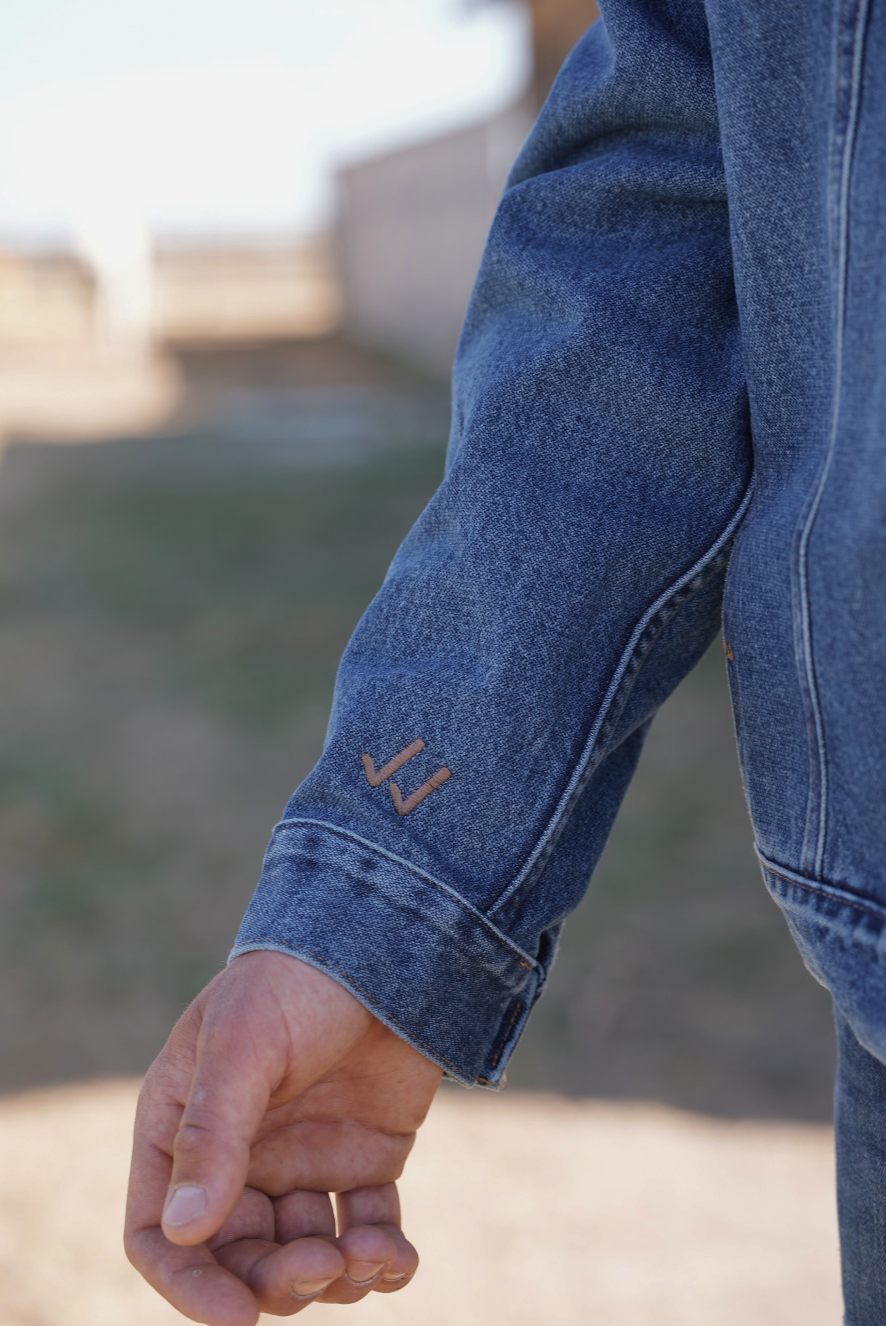 Close-up of a person wearing blue jeans with a brand logo on the cuff.