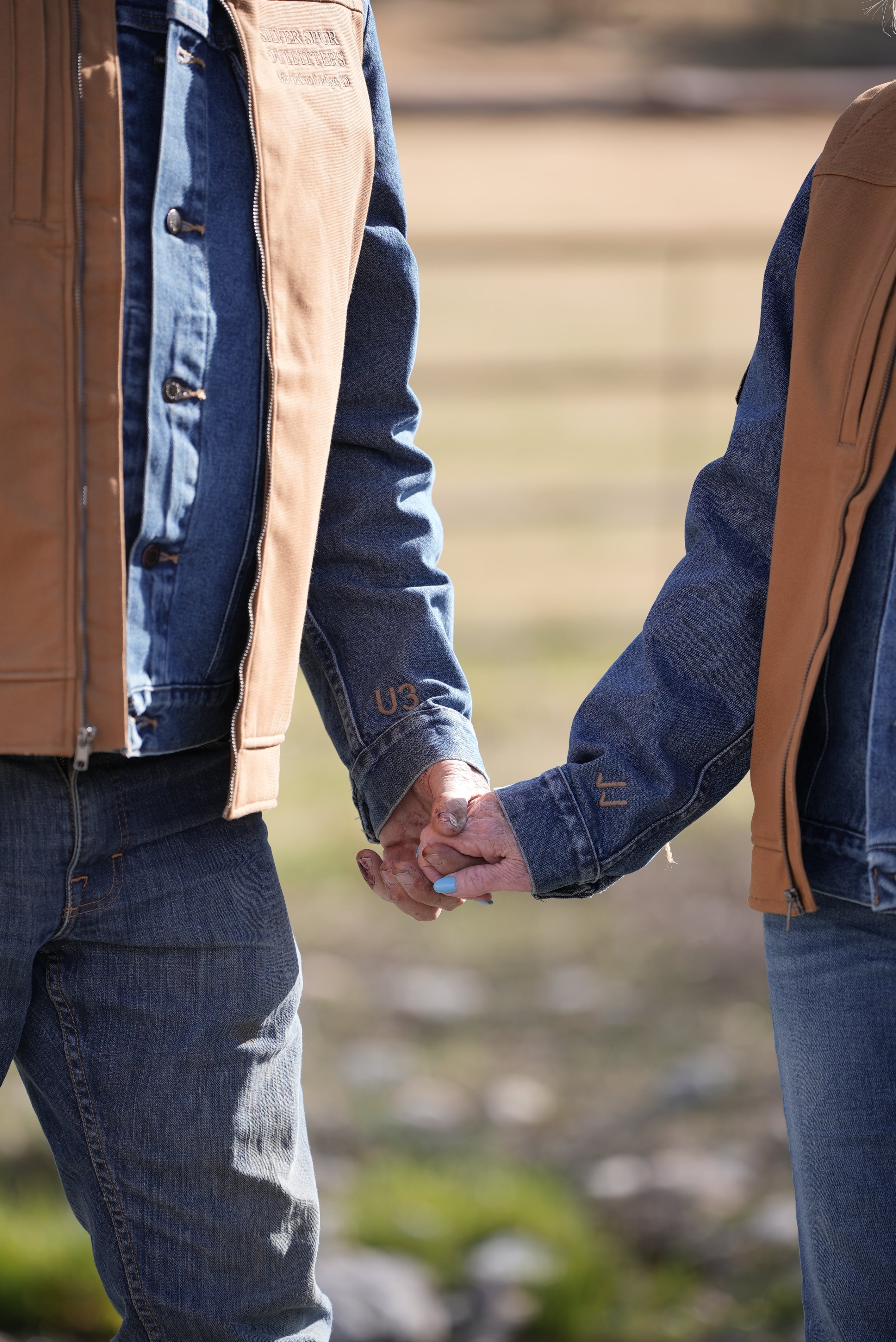 Two people holding hands with a blurred background