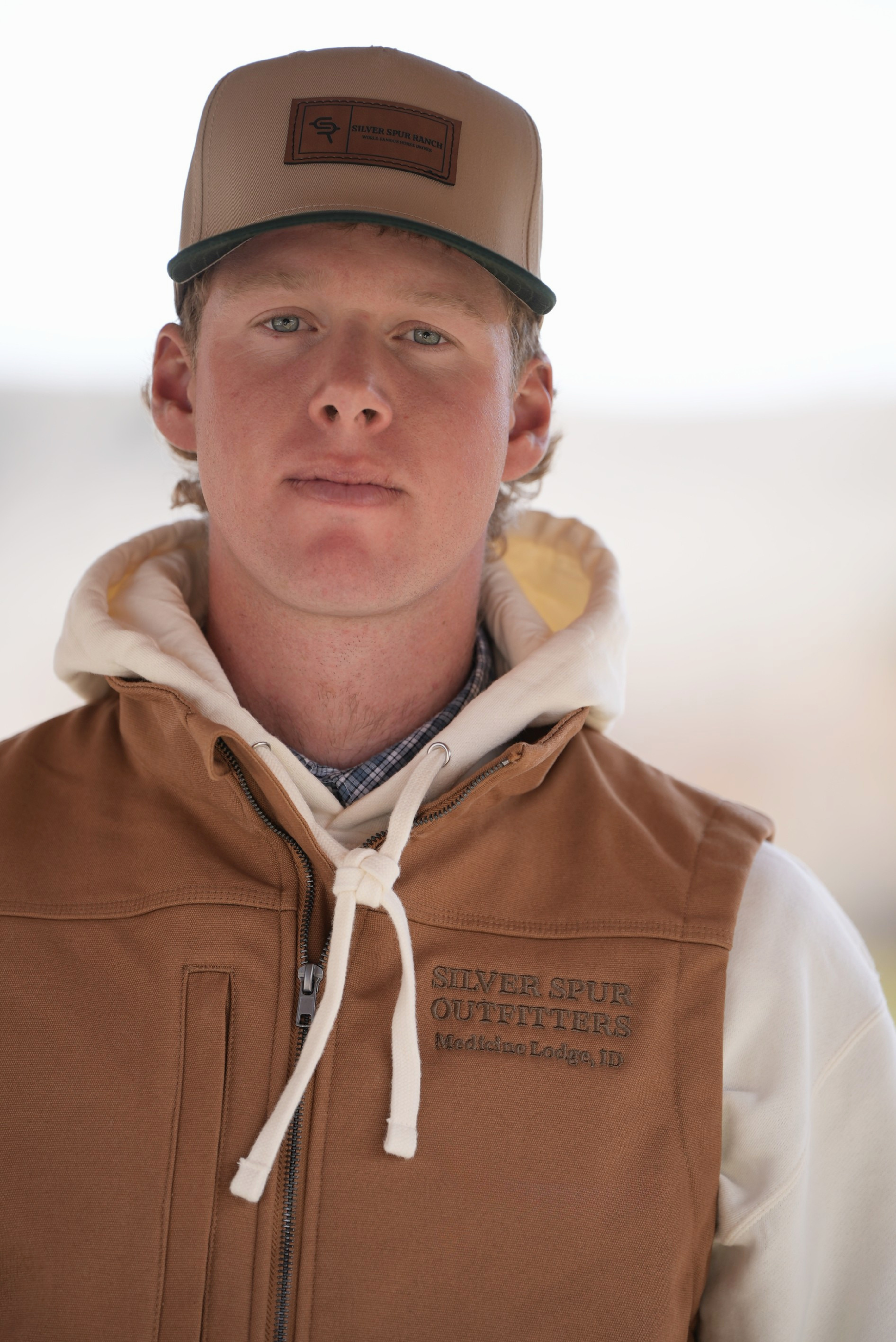 Man wearing a beige and green two tone cap with the Silver Spur Ranch logo.